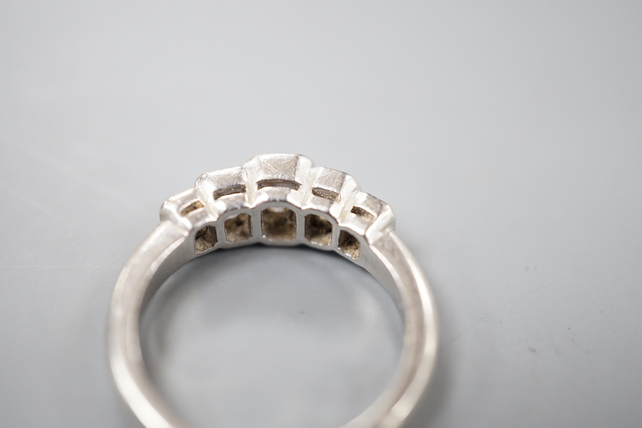 A modern platinum and graduated emerald cut five stone diamond set half hoop ring, size L, gross weight 6.4 grams.